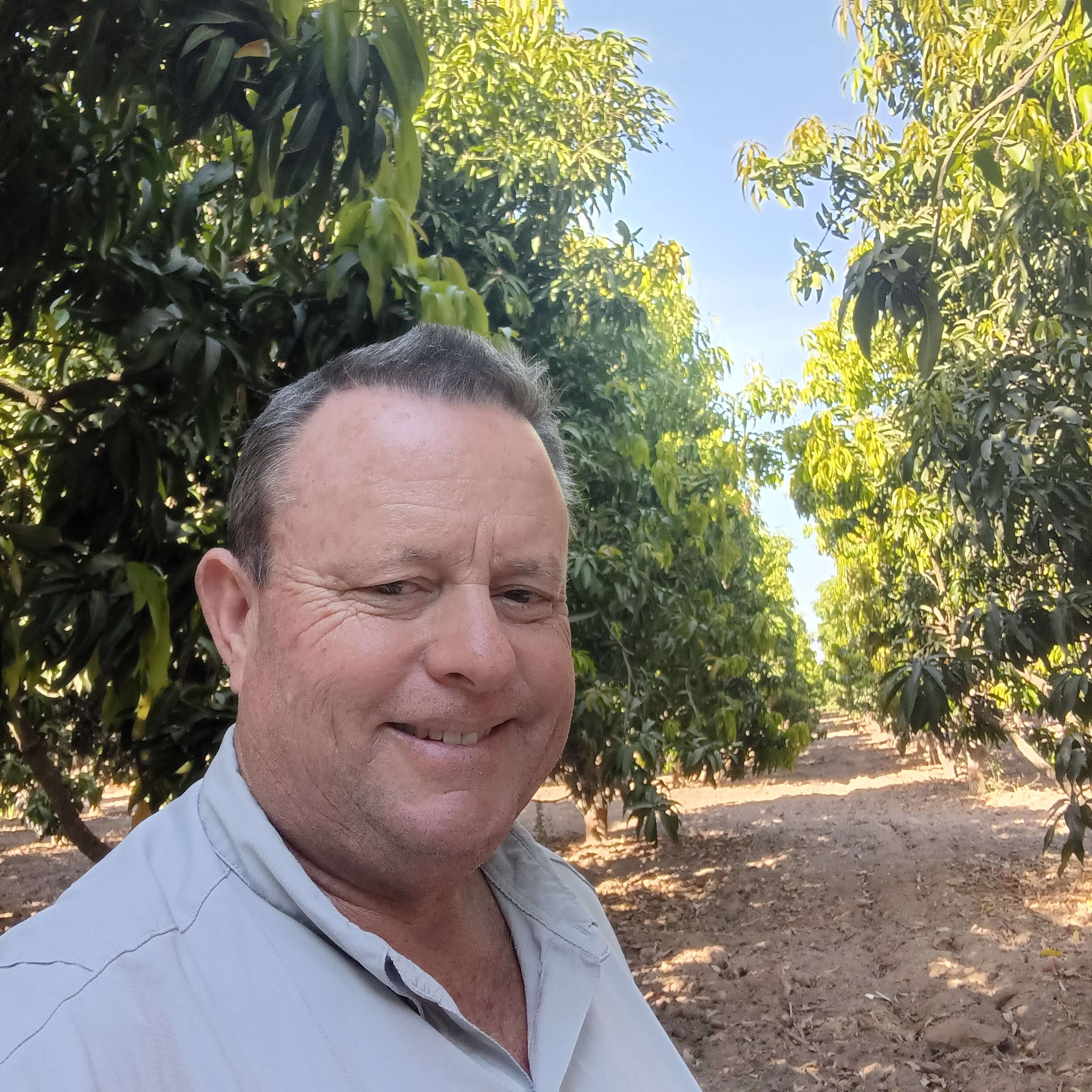 Man standing outdoors with greenery in the background
